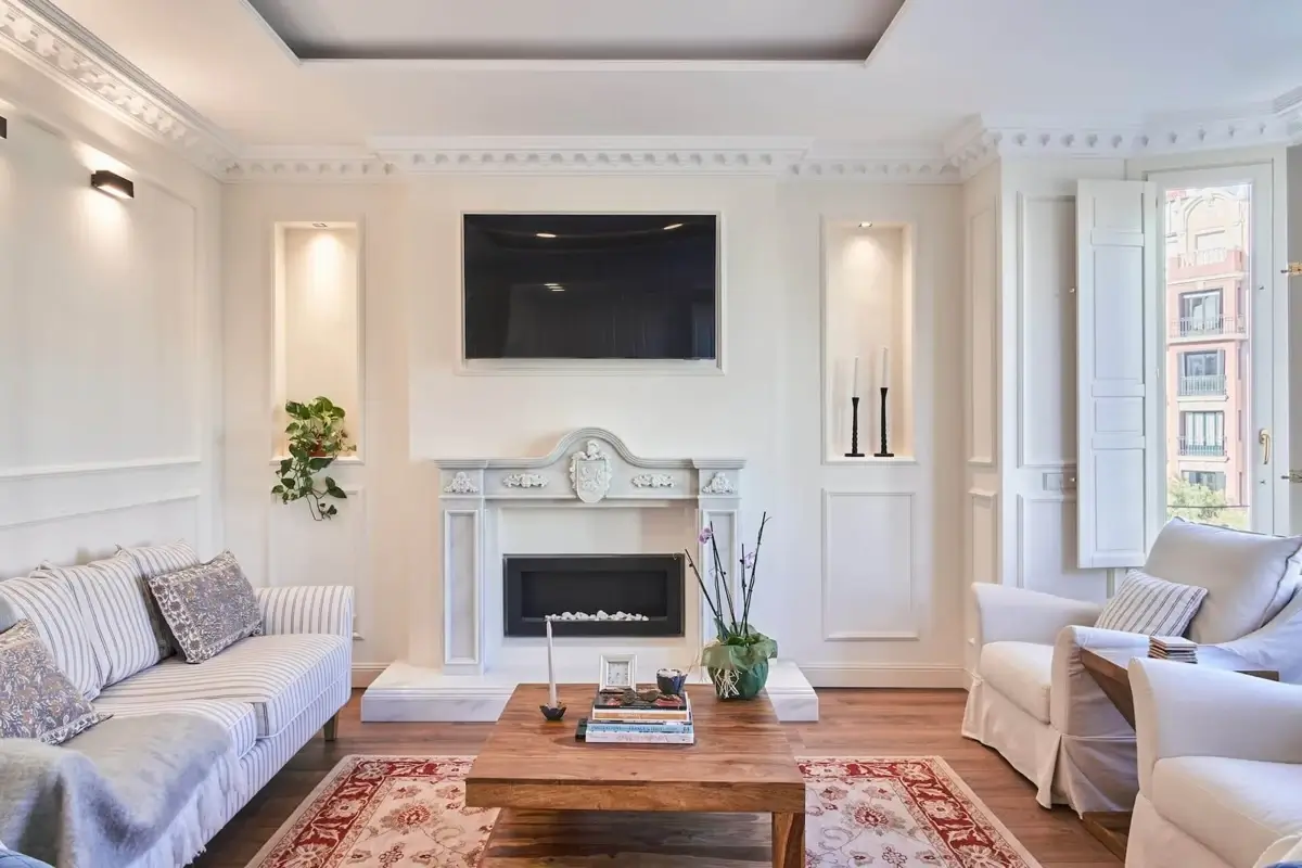 Salón reformado con chimenea, molduras y carpinterías blancas